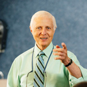 Dr. Gordon J. Christensen (facing forward) speaks with left hand lifted in gesture.